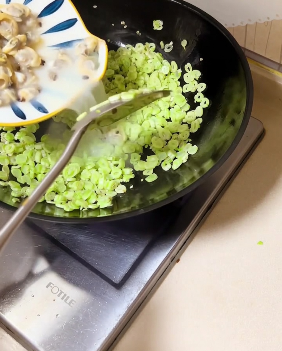 Muschelfleisch und Sud werden in den Wok zu den grünen Bohnen gegossen.