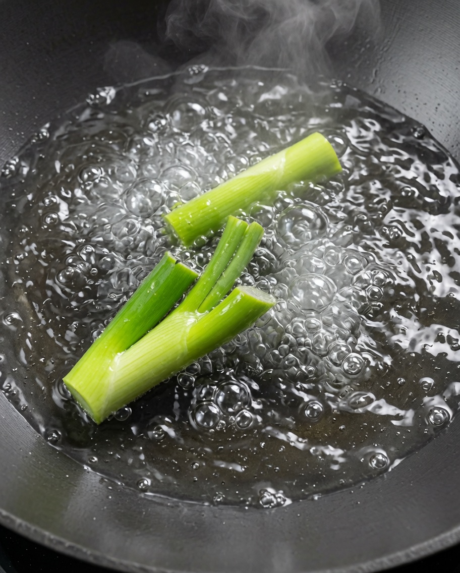 Flusskrebse werden in einem großen Wok mit kochendem Wasser und Frühlingszwiebeln kurz blanchiert.