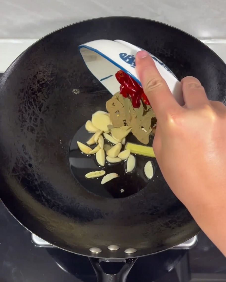 Eine Mischung aus Ingwer, Knoblauch und getrockneten Chilis brutzelt in heißem Öl in einem Wok.