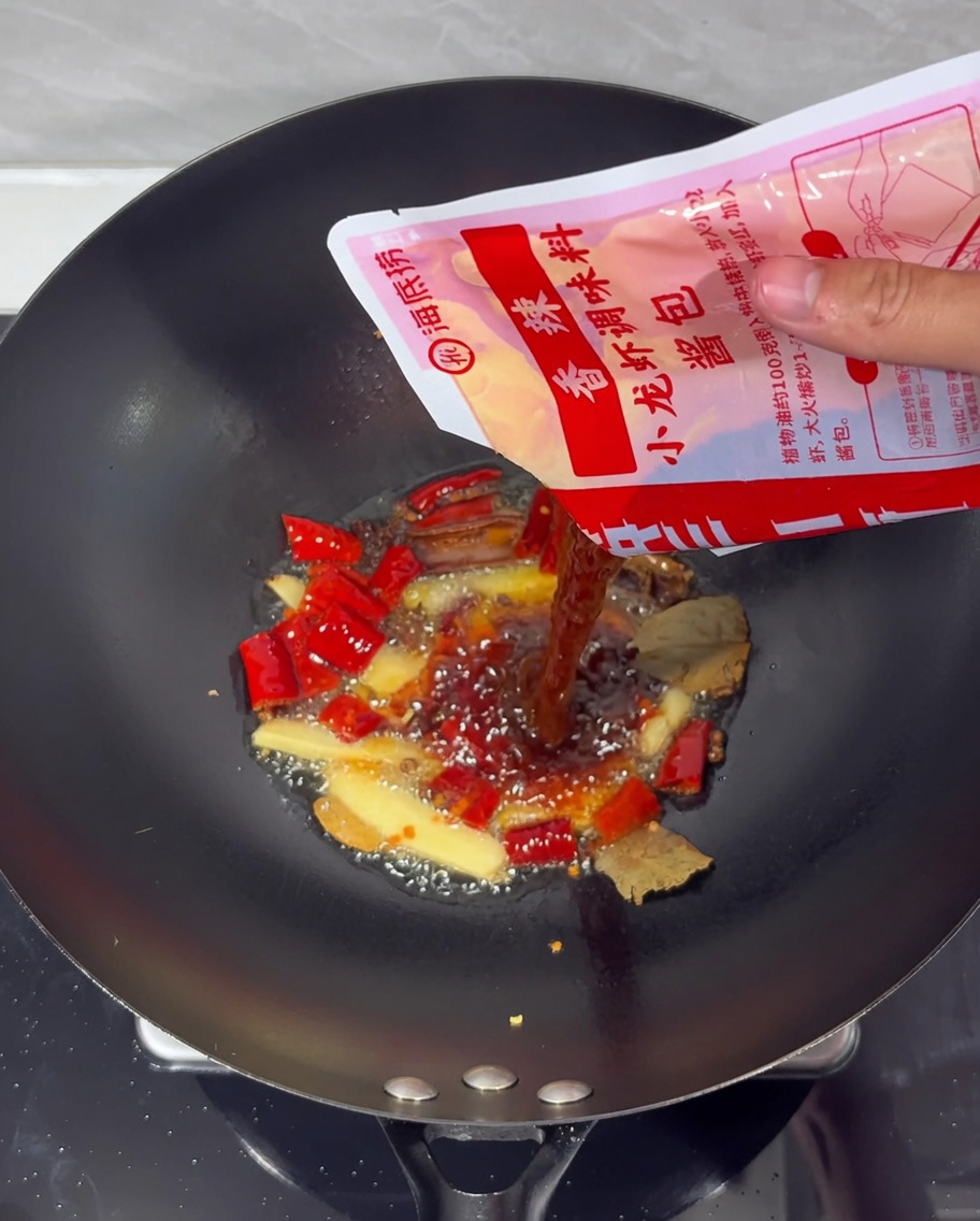 Würzpaste wird in einem Wok unter die scharfe Ölbasis gerührt.