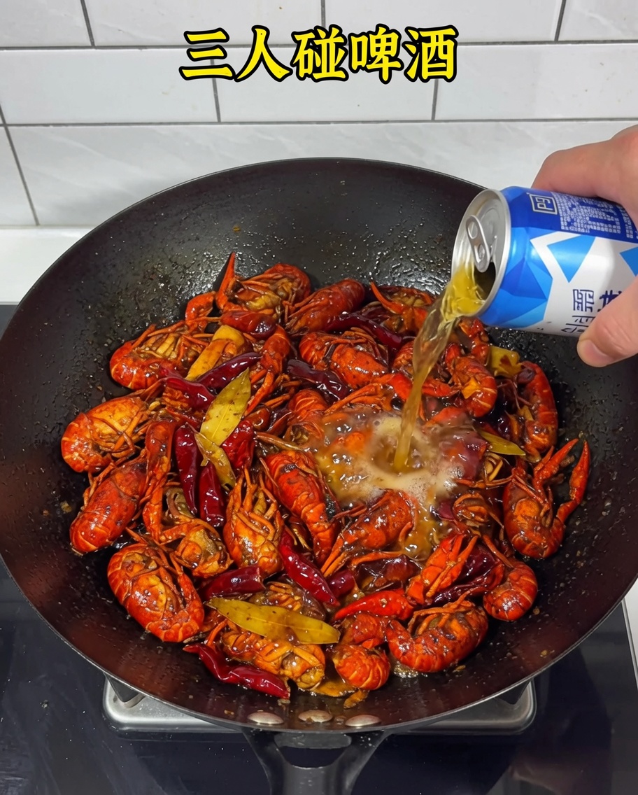 Bier wird über die Flusskrebse und die scharfe Basis in den Wok gegossen.