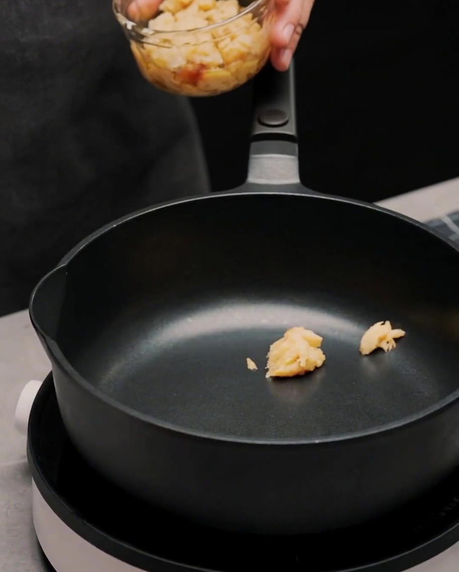 Olivenöl und Chiliflocken werden zur Knoblauchpaste in die Pfanne gegeben.