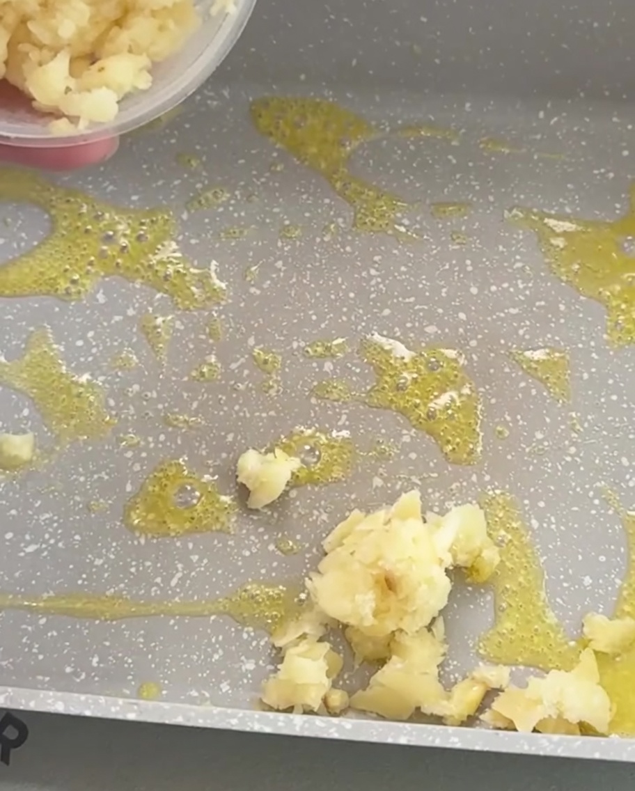 Gehackter Knoblauch brät in geschmolzener Butter in einer Pfanne goldbraun an.