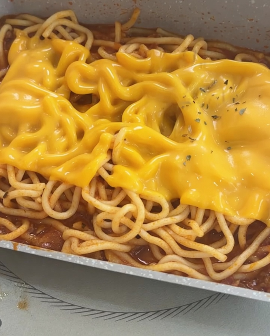 Spaghetti mit geschmolzenem Käse, verziert mit getrockneten Petersilienflocken.