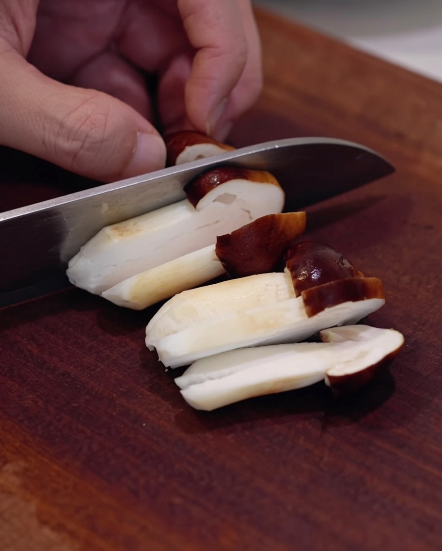 Frische Shiitake-Pilze werden auf einem Holzbrett geschnitten.