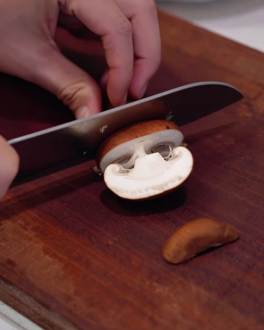 Bunte Paprika werden auf einem Holzbrett in Streifen geschnitten.