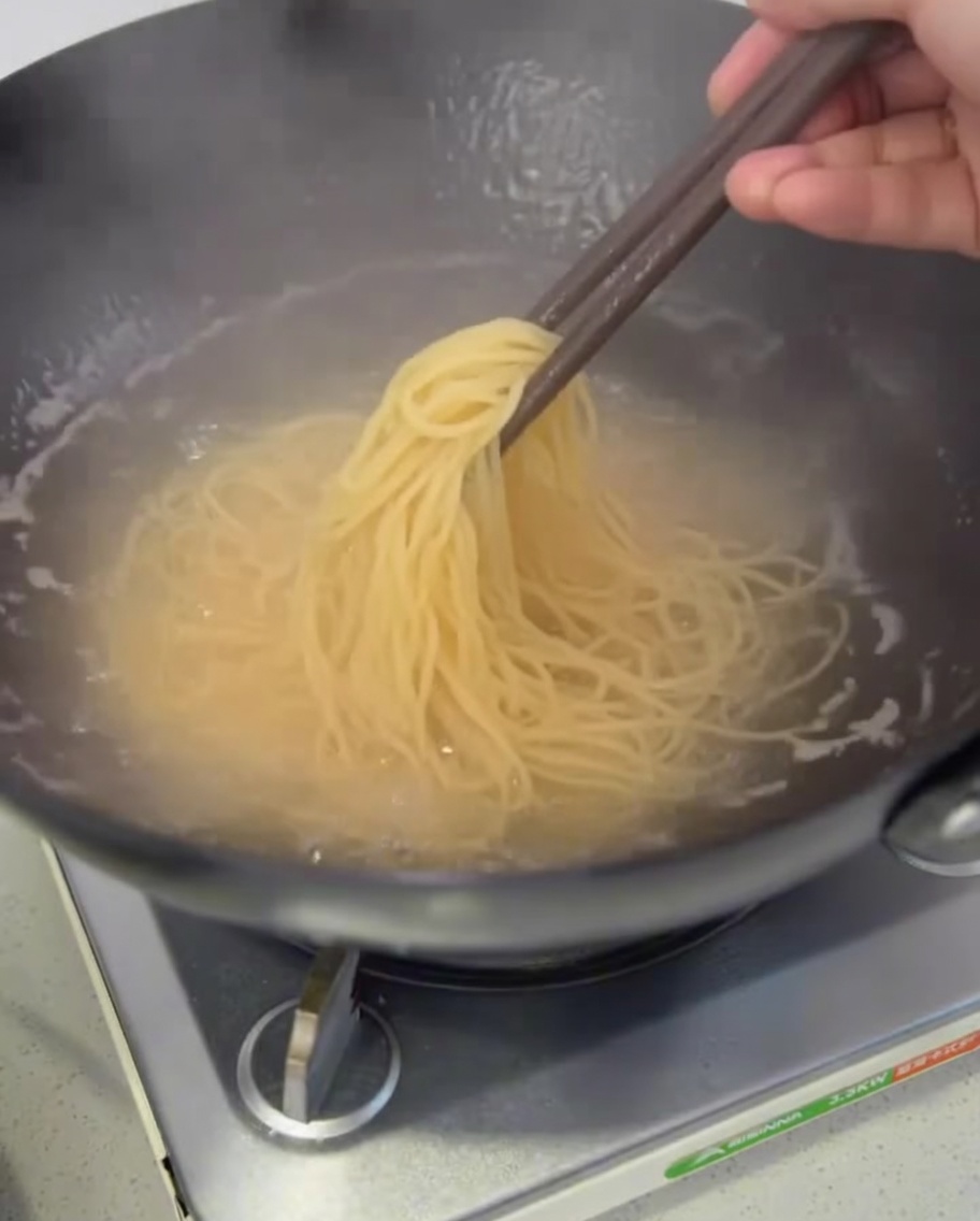 Gekochte Spaghetti werden aus dem Topf gehoben, um abzutropfen.