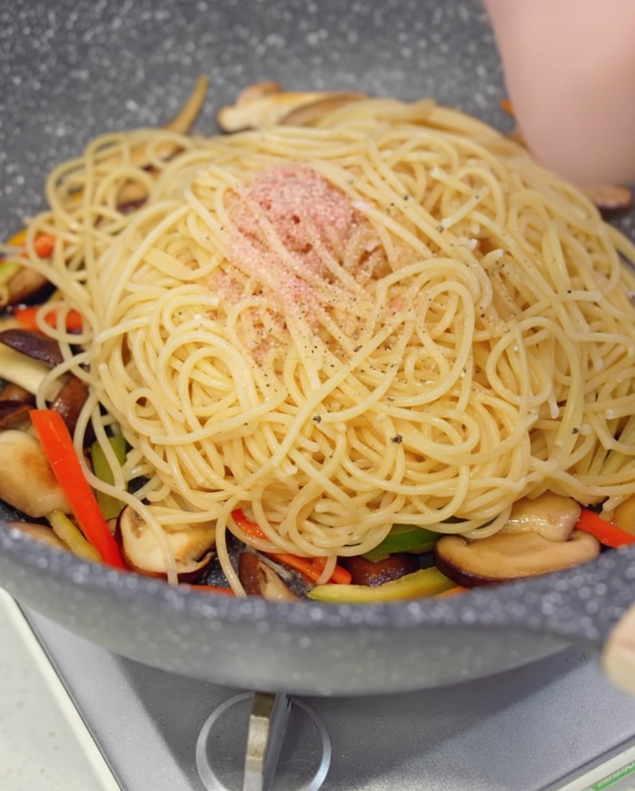 Schwarzer Pfeffer wird frisch über die Spaghetti in der Pfanne gemahlen.