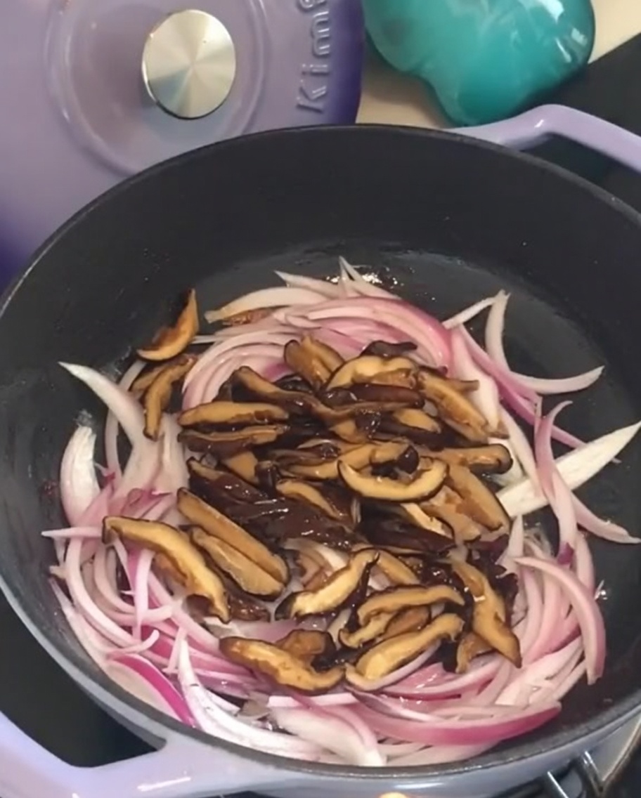 Geschnittene Shiitake-Pilze in der Pfanne bei den Zwiebeln.