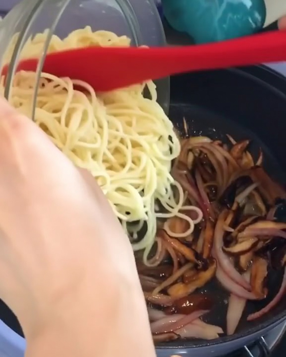 Gekochte Spaghetti werden in die Pfanne zur Sauce gegeben.
