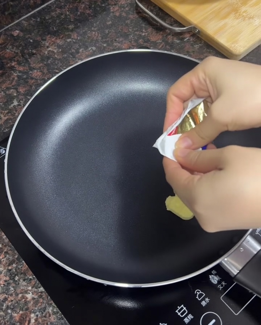 Butter schmilzt in einer heißen, schwarzen Antihaftpfanne.