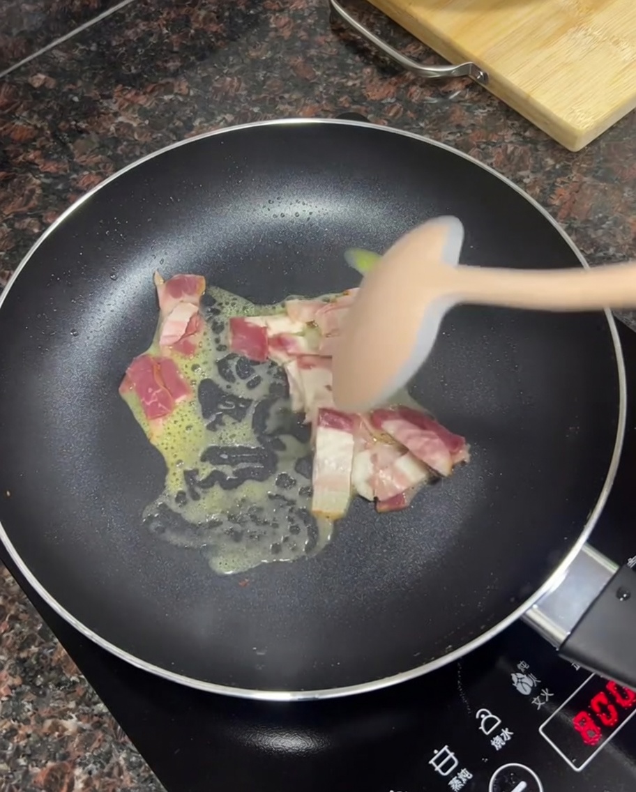 Speckwürfel braten in geschmolzener Butter in einer Pfanne.
