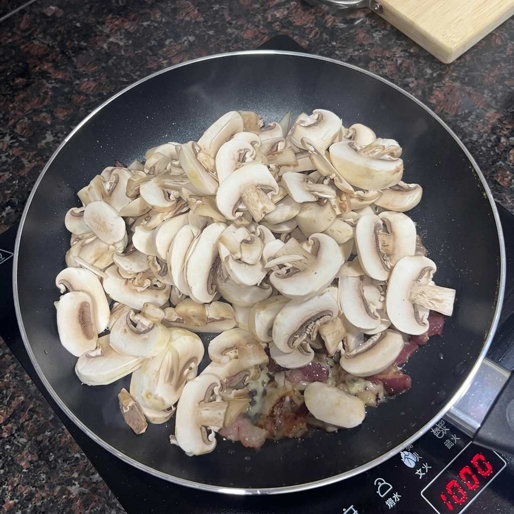 Geschnittene Champignons werden zu Speck und Knoblauch in die Pfanne gegeben.