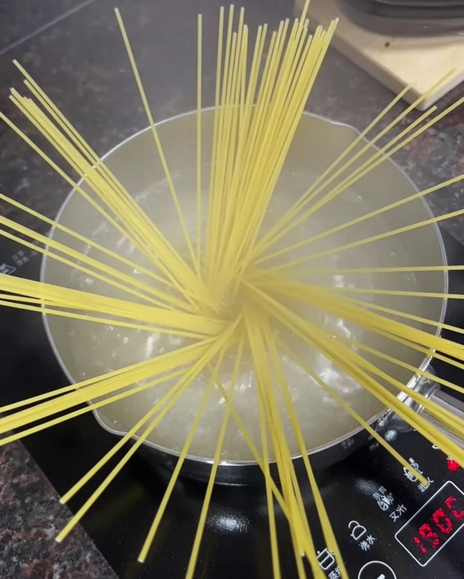 Spaghetti in einem Topf mit sprudelnd kochendem Wasser auf dem Herd.