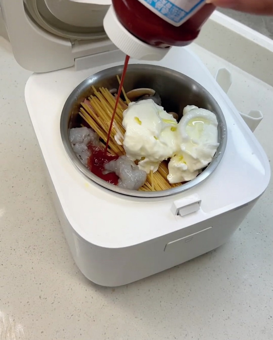 Olivenöl und Tomatensoße werden in den Reiskochertopf gegeben, bereit zum Garen.
