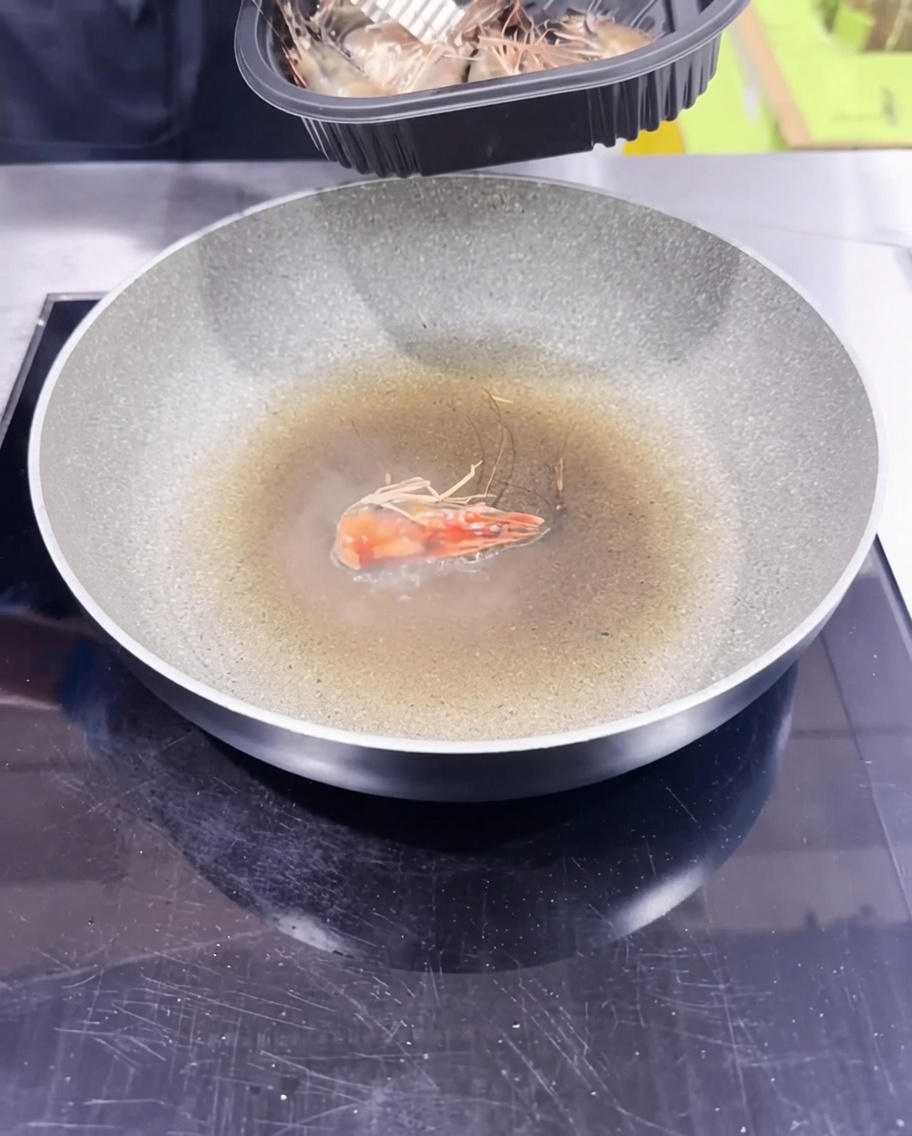 Garnelenköpfe werden in einer Pfanne sautiert, um ein aromatisches Garnelenöl zu erzeugen.