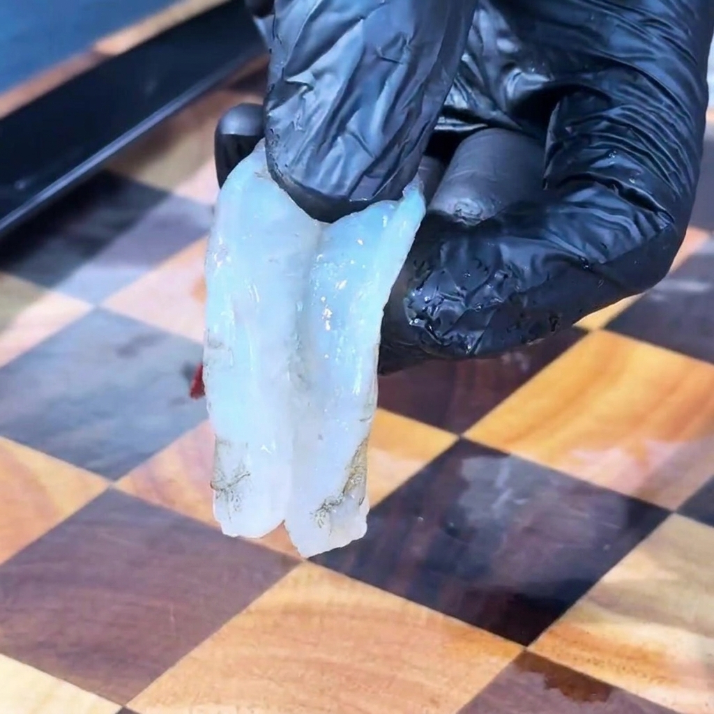 Nahaufnahme von rohen Garnelen in einer Schüssel, die mit Salz, Pfeffer und Chilipulver gewürzt werden.