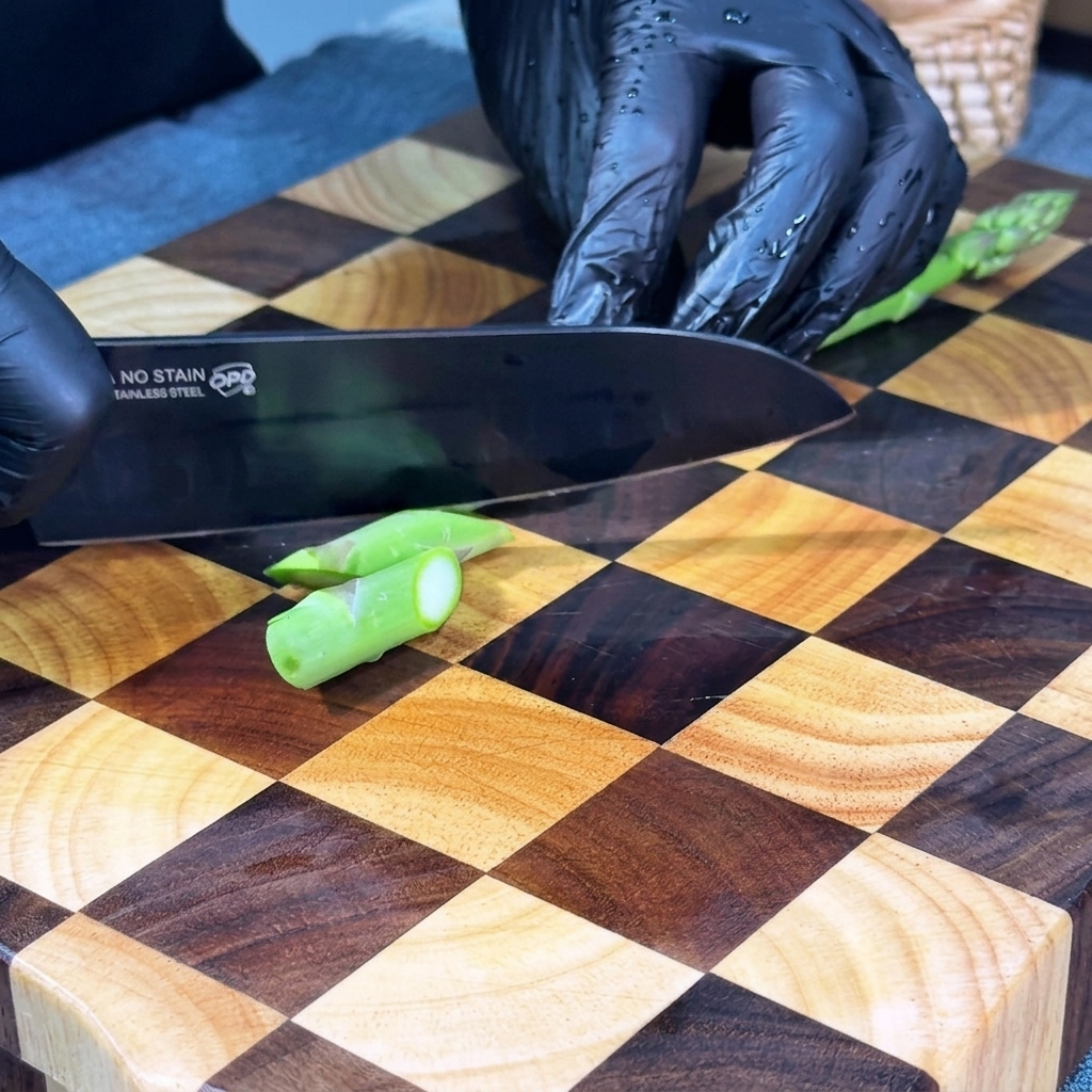 Frischer Spargel wird in kleine, gleichmäßige, diagonale Stücke auf einem Holzschneidebrett geschnitten.