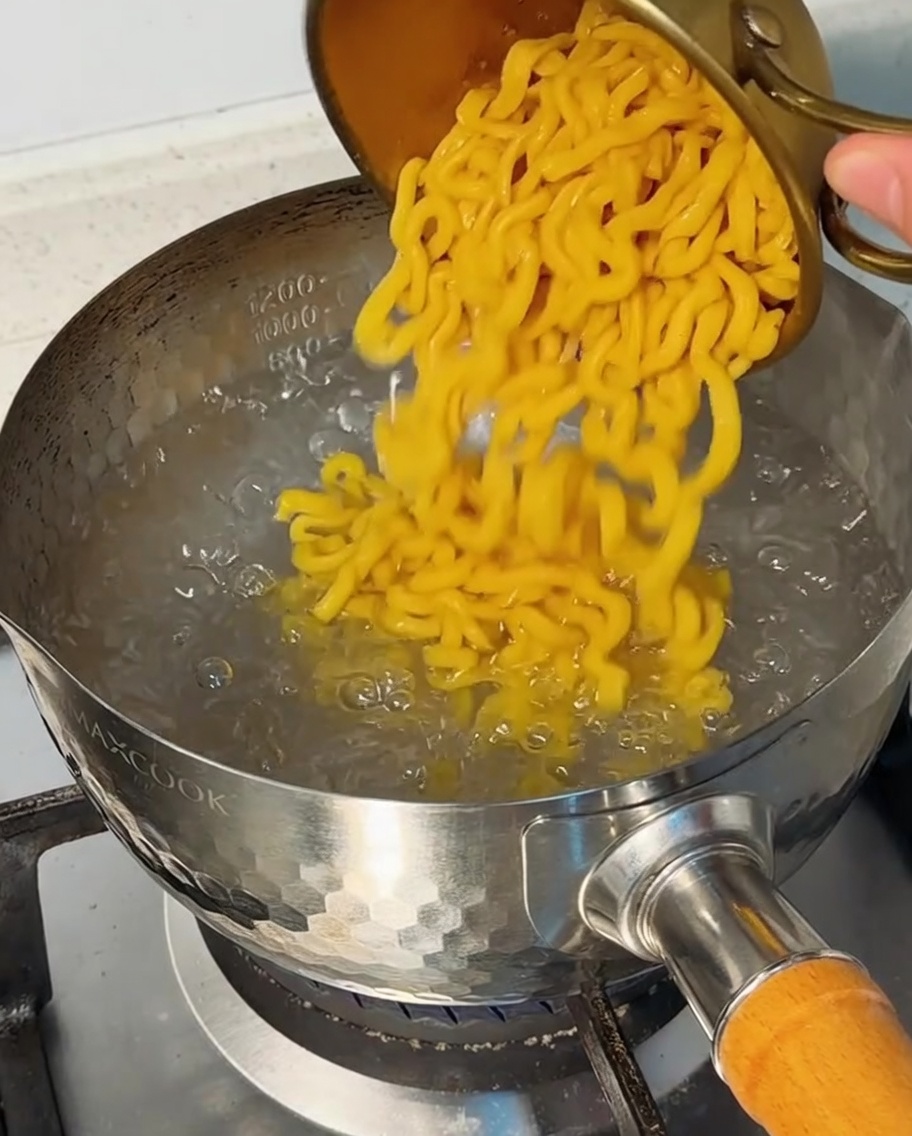 Makkaroni werden in einen Topf mit sprudelnd kochendem Wasser gegeben.