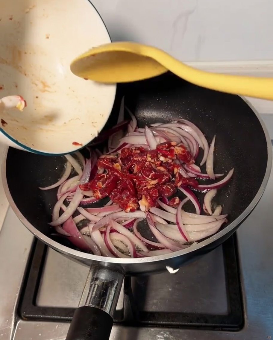 Mariniertes Rindfleisch wird in die Pfanne gegeben und mit den weichen Zwiebeln vermischt.