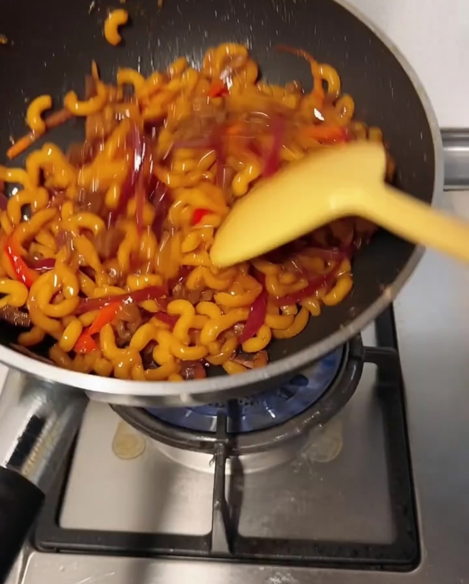 Die Makkaroni-Mischung wird im Wok gerührt, während der Käse schmilzt und die restlichen Zutaten cremig überzieht.