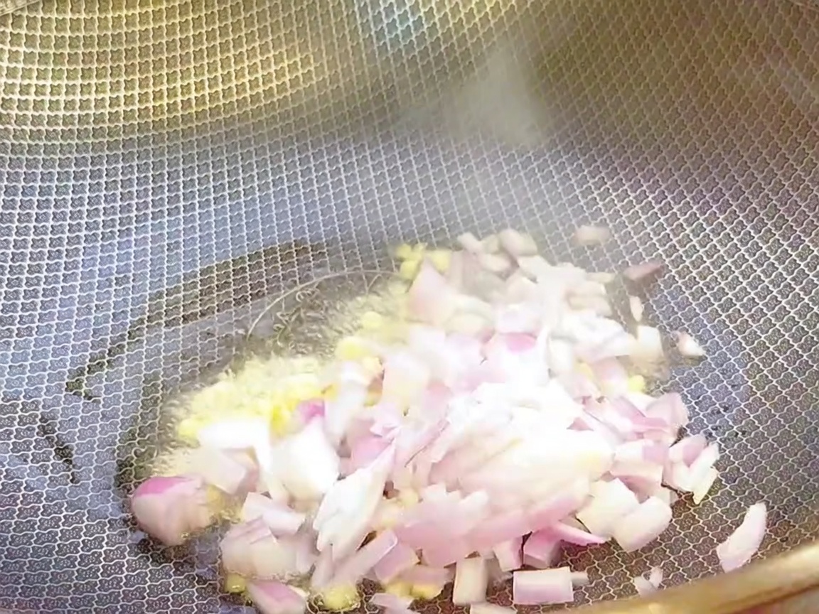 Gehackter Knoblauch und Zwiebeln werden in einem heißen Wok mit Öl angebraten.