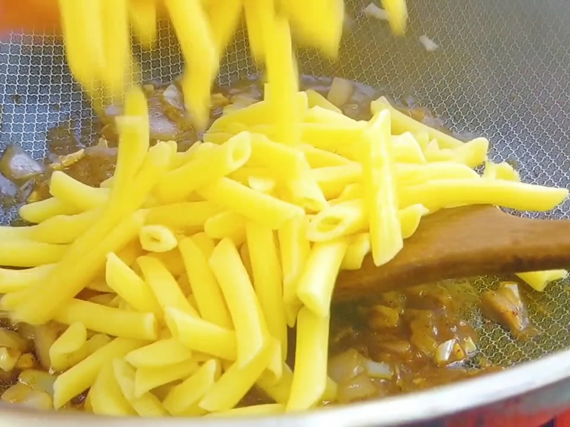 Gekochte Penne-Pasta wird in den Wok zur Pfeffersaucen-Basis gegeben.