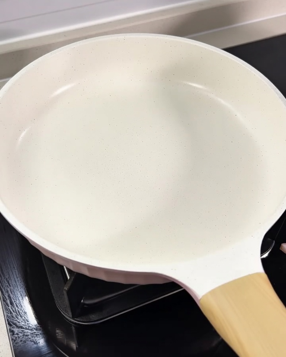 Gewürfelter Guanciale brät in einer hellen Pfanne im eigenen Fett.