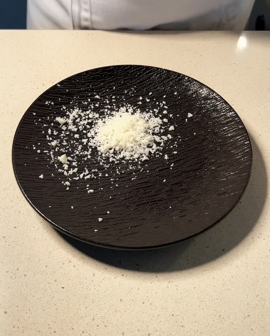 Frisch geriebener Parmesan und Pecorino auf einem dunklen Teller.
