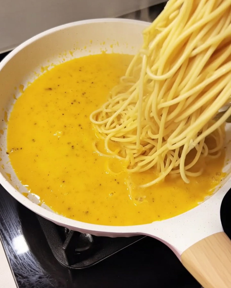 Gekochte Spaghetti werden in die Sauce gegeben.