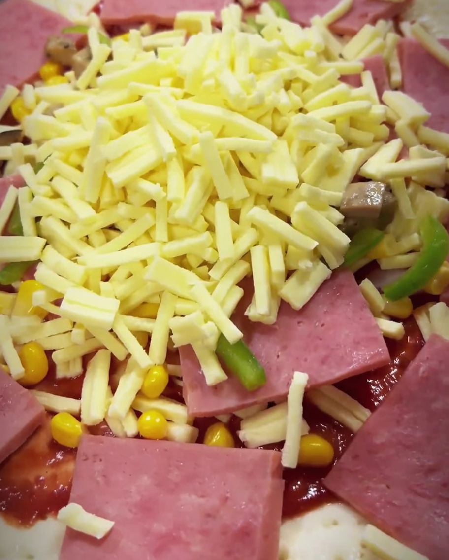 Die fertig belegte Pizza wird in den heißen Ofen geschoben.