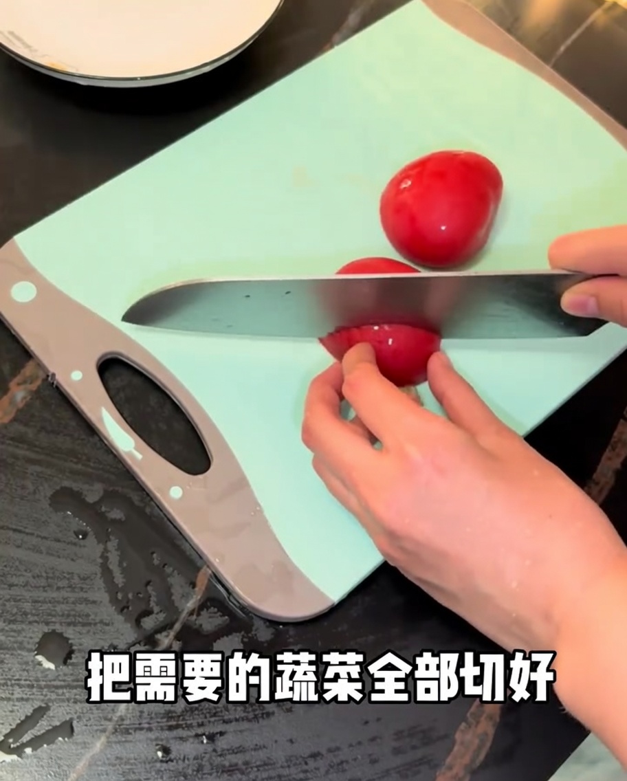 Frische rote Tomaten, die mit einem Kochmesser auf einem grünen Schneidebrett in Stücke geschnitten werden.