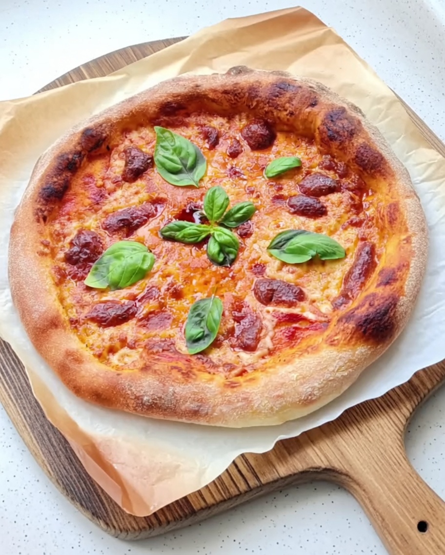 Tomatensauce wird auf dem Teigfladen verteilt.
