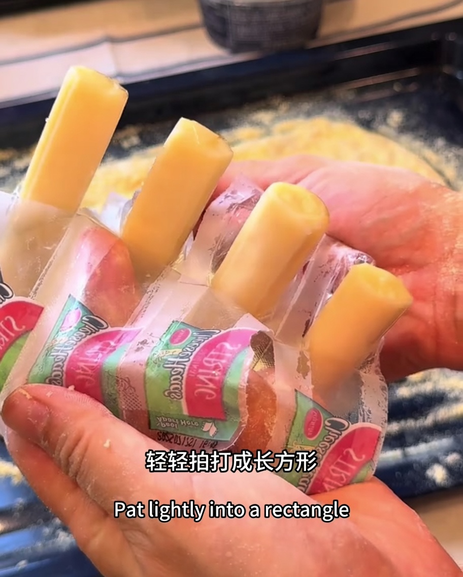 Mozzarella-Sticks sind entlang der Ränder des rechteckigen Pizzateigs positioniert.