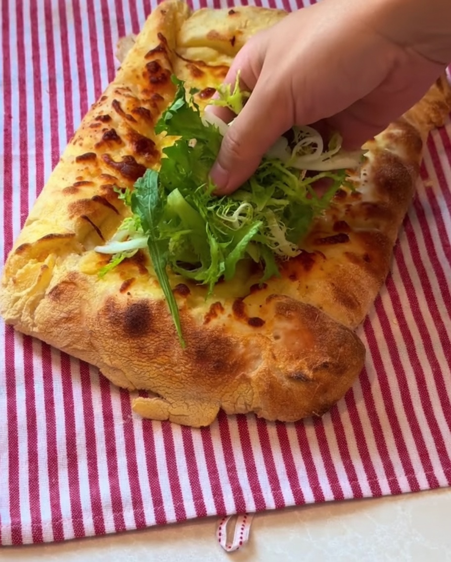 Frischer Blattsalat und hauchdünner Prosciutto werden auf der gebackenen Pizza verteilt.