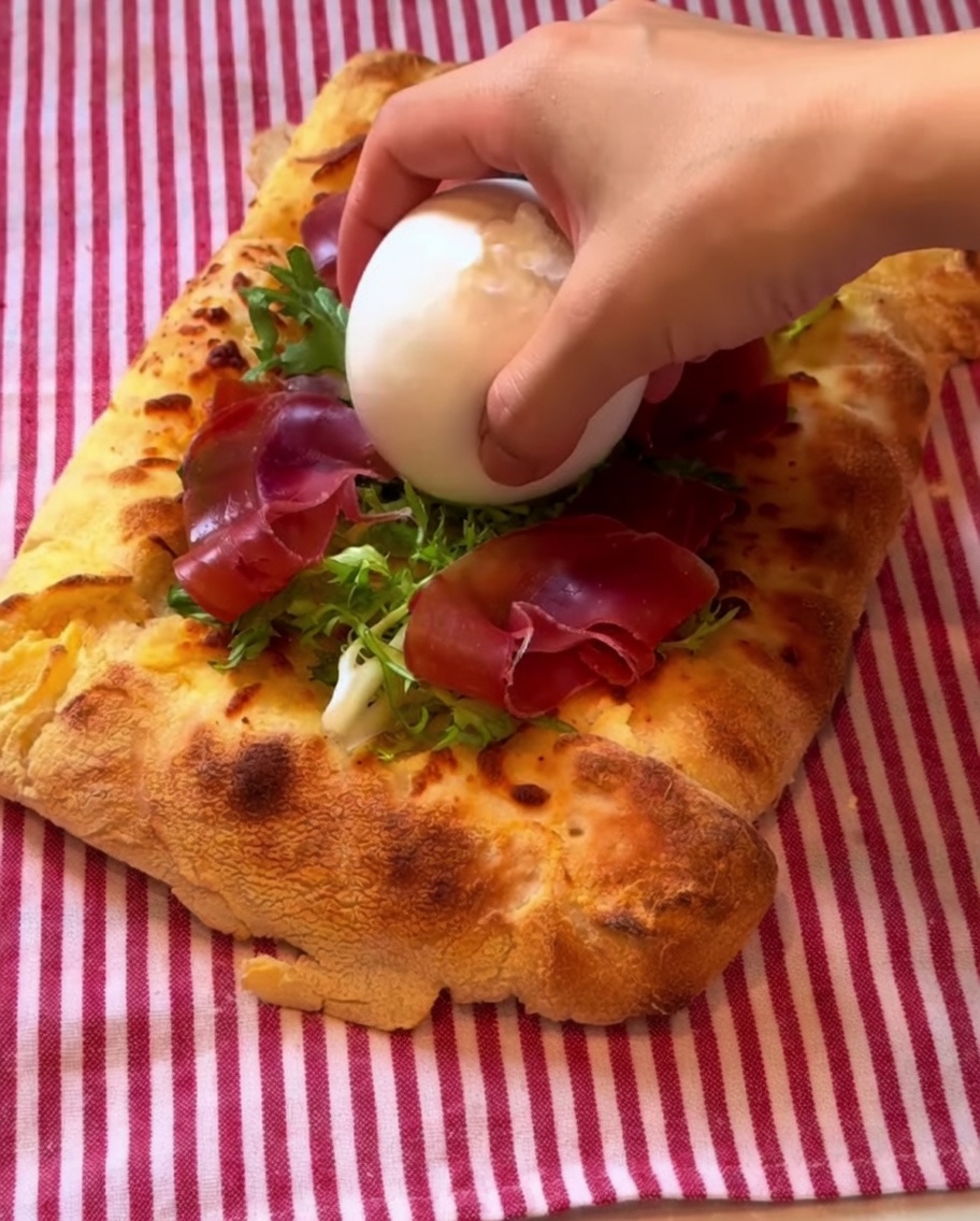 Eine Kugel Burrata in der Mitte der Pizza, verfeinert mit Balsamico-Dressing.