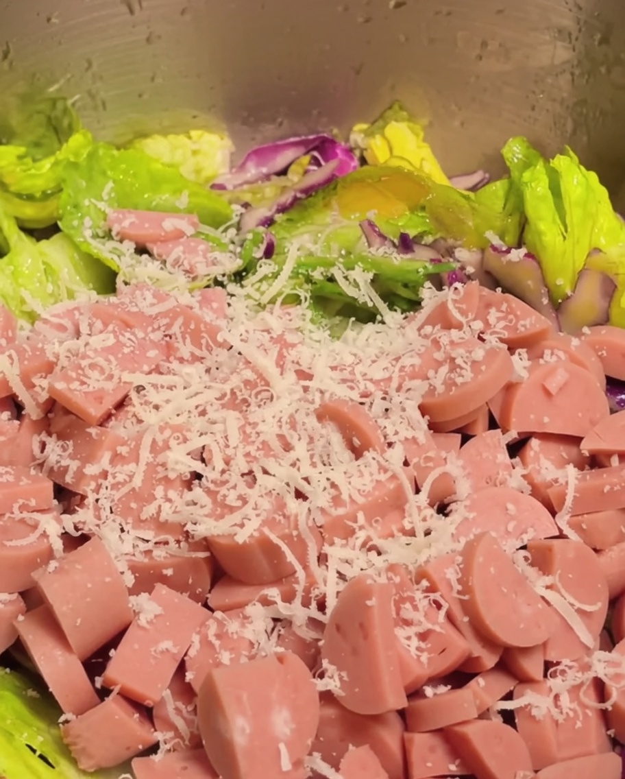 Gewürfelter Schinken und geriebener Parmesan werden zur Gemüsesalatmischung gegeben.