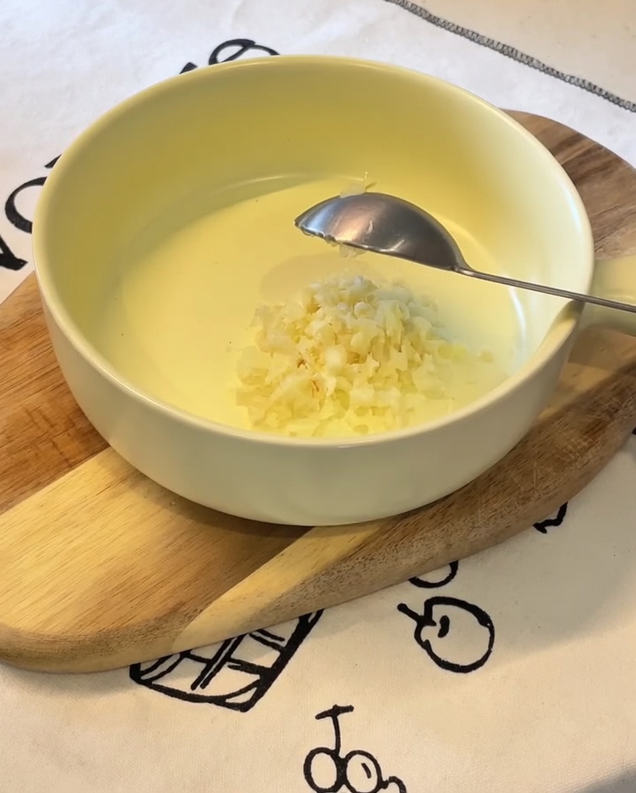 Gehackter Knoblauch, Frühlingszwiebeln, japanische Mayonnaise, Eigelb und Ramen-Würzpulver in einer gelben Schüssel.