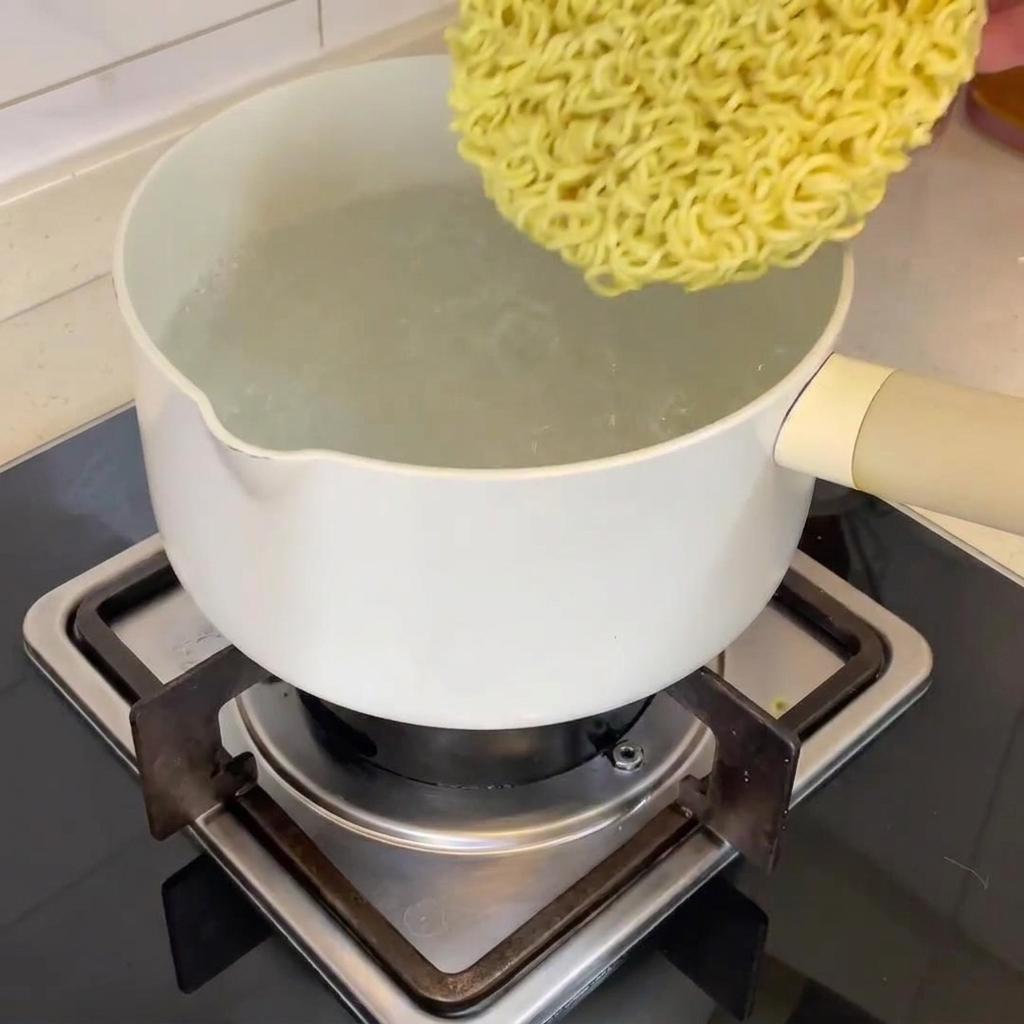 Ein Block getrocknete Ramen-Nudeln wird in einen Topf mit kochendem Wasser gegeben.