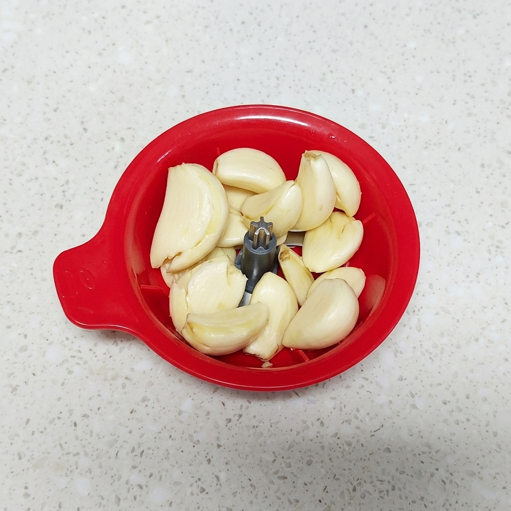 Knoblauchzehen in einem kleinen manuellen Zerkleinerer.