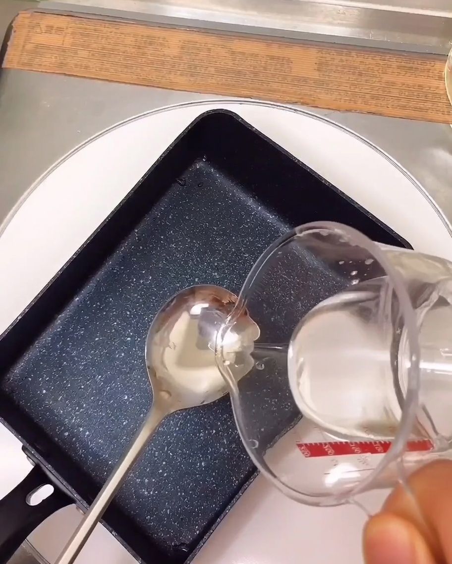 Die Zutaten für die Marinade köcheln in einer rechteckigen Pfanne auf dem Herd.