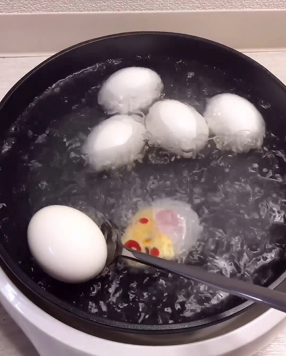 Gekochte Eier werden aus dem Topf genommen und in eine Schüssel mit Eiswasser gelegt.
