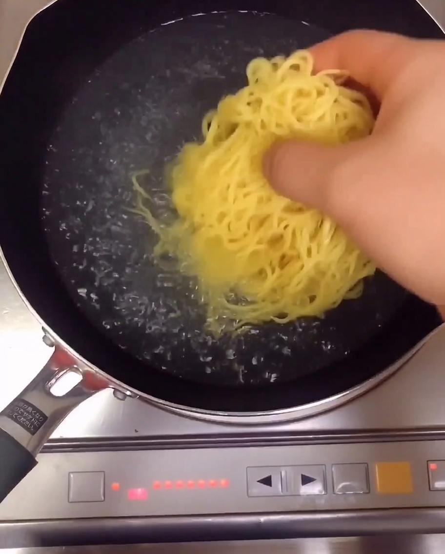 Gelbe Ramen-Nudeln kochen in einem Topf mit Wasser auf dem Herd.