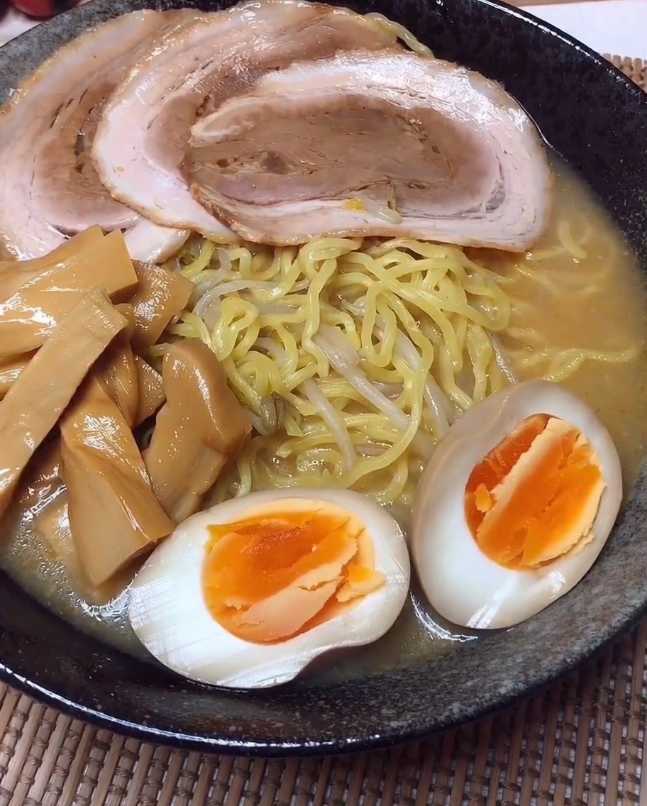 Eine angerichtete Ramen-Schale mit geordneten Reihen aus Fleisch, Bambussprossen und halbierten Eiern.