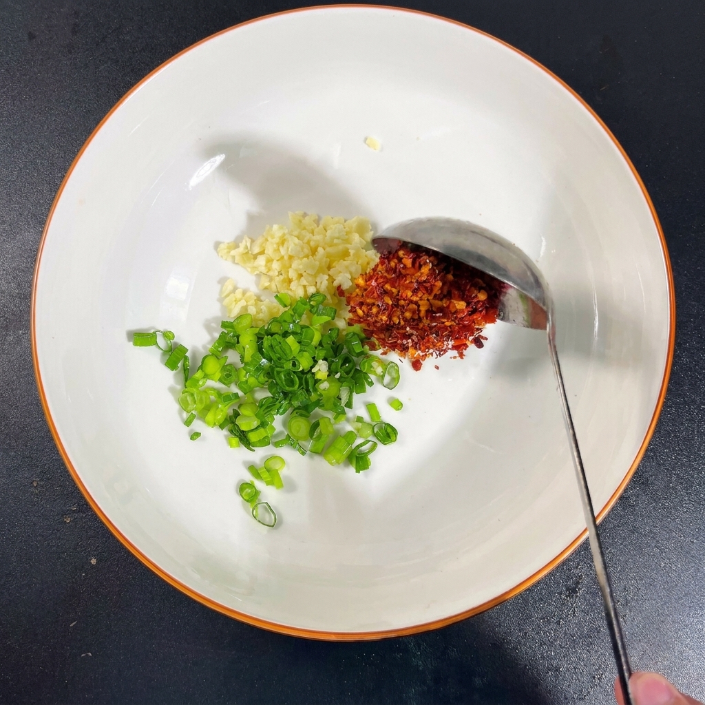 Eine Schüssel mit Knoblauch, Frühlingszwiebeln, Gewürzen und Sojasauce.