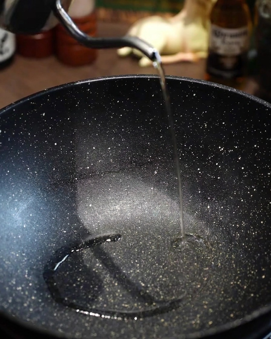 Speiseöl wird in eine vorgeheizte, leere schwarze Pfanne gegeben.