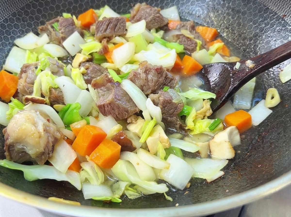 Wasser wird über das Rindfleisch und das Gemüse in einer Pfanne gegossen, bereit für eine lange Kochzeit.