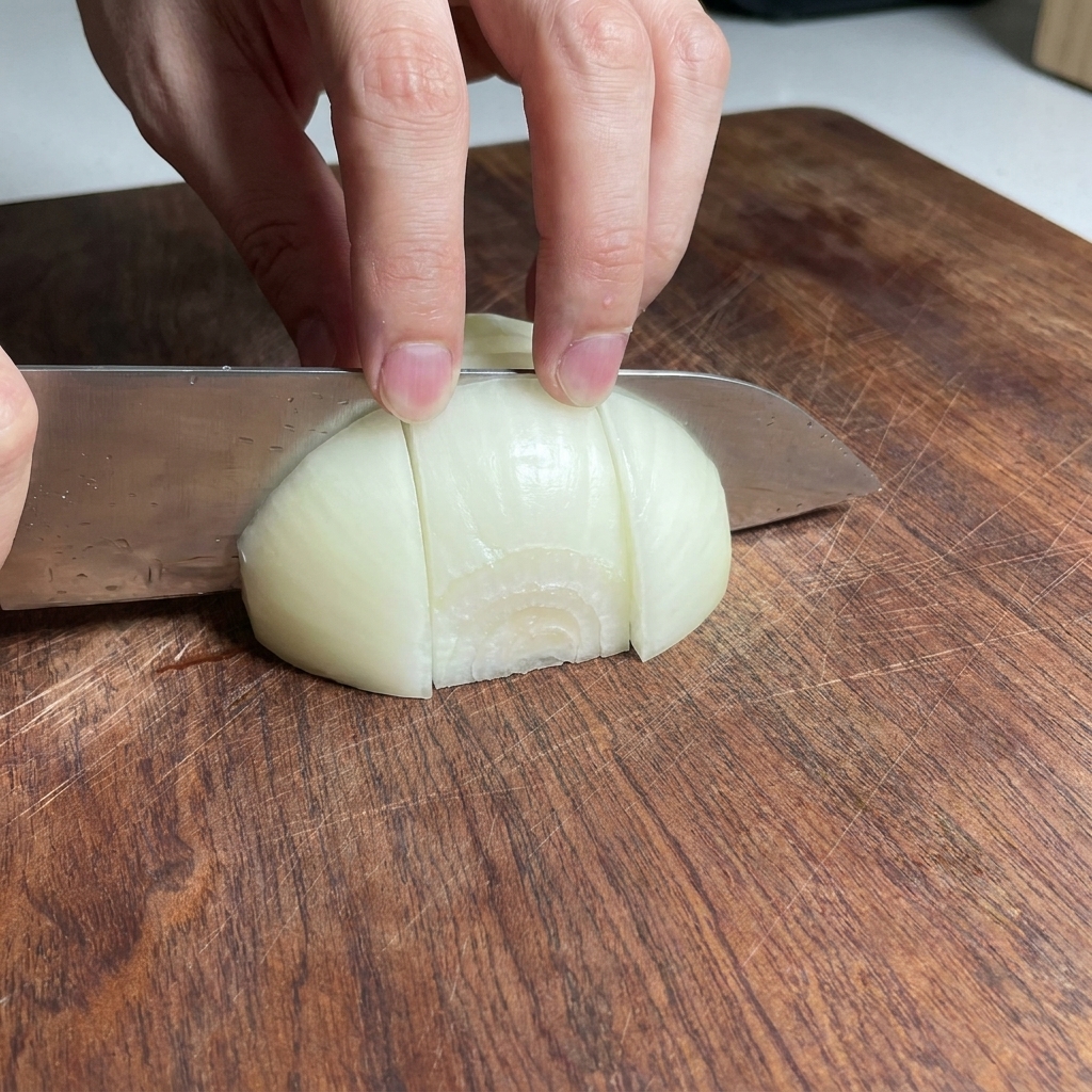 Zwiebelstücke auf einem Holzschneidebrett.
