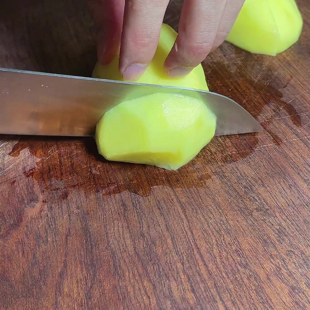 Gewürfelte Kartoffelstücke auf einem Holzschneidebrett.