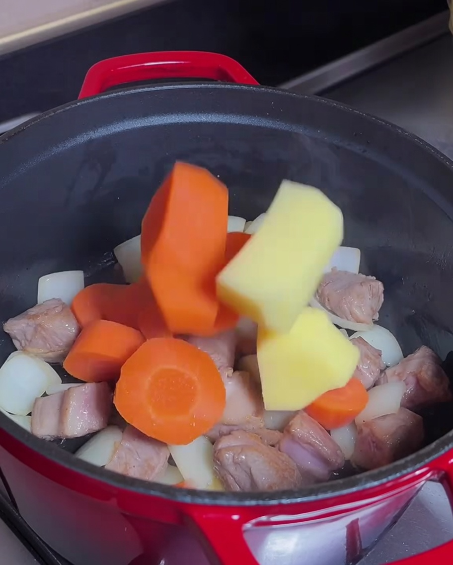 Karotten und Kartoffeln im Topf mit Fleisch.